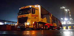 A transport truck parked at a warehouse at night